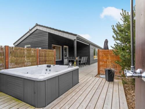 un bain à remous sur une terrasse en bois avec une maison dans l'établissement Holiday Home Soili - 1-2km from the sea by Interhome, à Blåvand