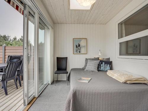 - une chambre avec un lit et un balcon avec une chaise dans l'établissement Holiday Home Skakke - 900m from the sea by Interhome, à Blåvand