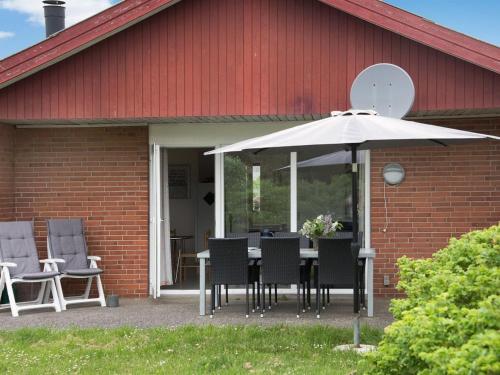 a table with chairs and an umbrella in front of a building at Holiday Home Dværg - 350m from the sea by Interhome in Ringkøbing