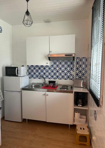 appartement hyper centre في ناربون: مطبخ بخزائن بيضاء ومغسلة
