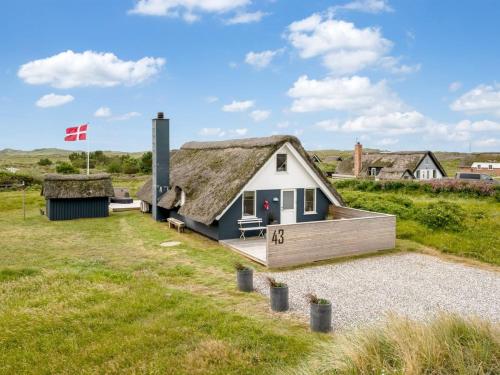a house with a thatched roof and a flag at Holiday Home Hen - 400m from the sea by Interhome in Ringkøbing