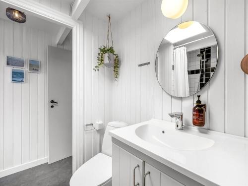 a white bathroom with a sink and a mirror at Holiday Home Hen - 400m from the sea by Interhome in Ringkøbing