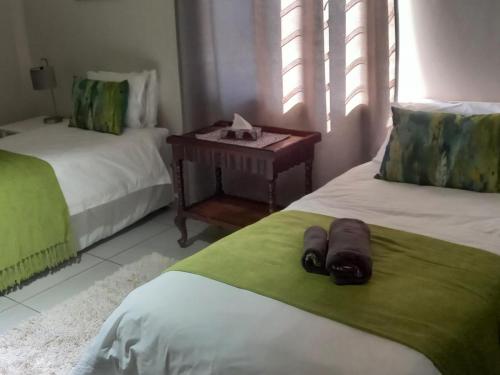 a room with two beds and a night stand with a table at Rivergrace Farm in Robertson
