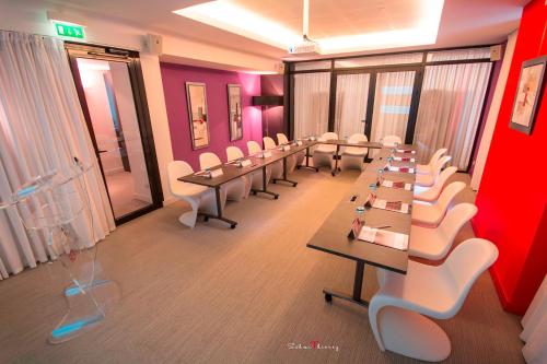a conference room with long tables and white chairs at Le Rex Hôtel in Tarbes