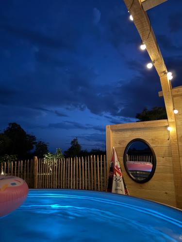 ein Schwimmbad in der Nacht mit einem Holzzaun in der Unterkunft Lodge avec Spa extérieur privé en option et mini-ferme sur place in Saint-Laurent-dʼAndenay