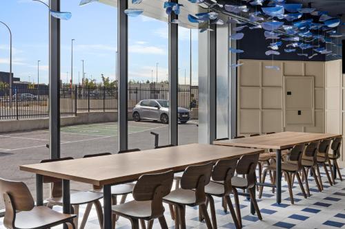 a row of tables and chairs in a room with windows at B&B HOTEL Alicante Aeropuerto in Alicante