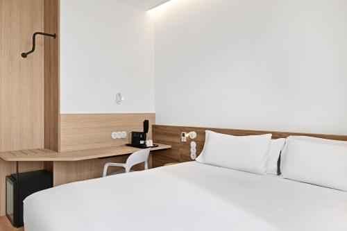 a bedroom with a white bed and a desk at B&B HOTEL Alicante Aeropuerto in Alicante