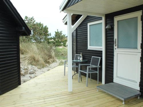 a wooden deck with a table and chairs on a house at Holiday Home Martti - from the sea by Interhome in Bjerregård