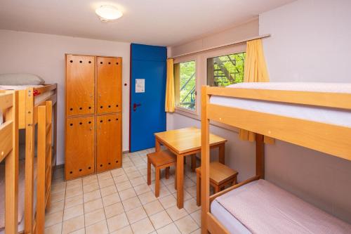 a dorm room with bunk beds and a desk and a table at Delémont Youth Hostel in Delémont