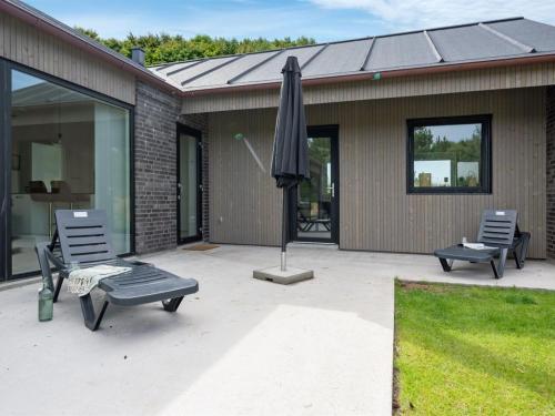 un patio con 2 sillas y una sombrilla en Holiday Home Pejo - 950m from the sea by Interhome, en Ringkøbing