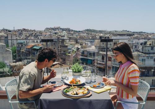 a man and woman sitting at a table eating food at Novotel Athens in Athens