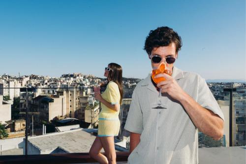 a man and a woman standing on a ledge with a drink at Novotel Athens in Athens