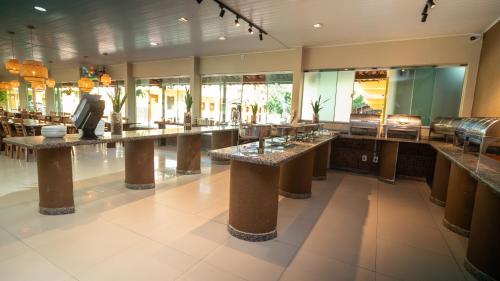 a restaurant with long tables in a large room at Pousada Itajuípe- Unidade Itabuna-Ba in Itabuna