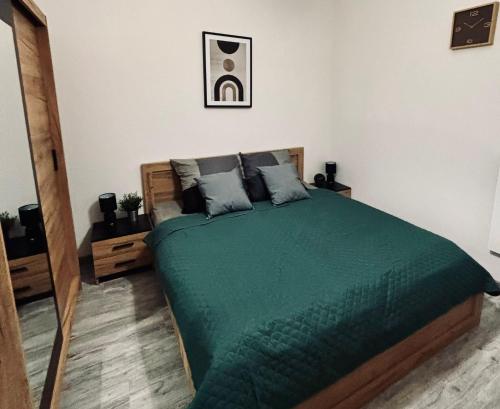 ein Schlafzimmer mit einem Bett mit einer grünen Bettdecke in der Unterkunft Apartament 87 in Jelenia Góra