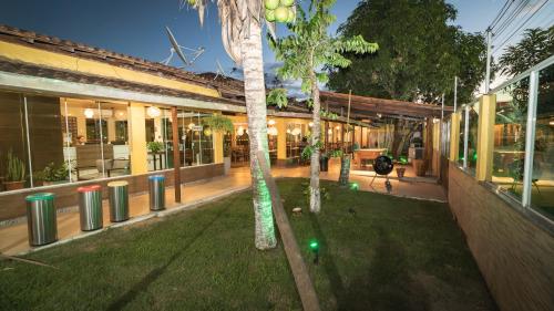 a building with a palm tree in the middle of a yard at Pousada Itajuípe- Unidade Itabuna-Ba in Itabuna