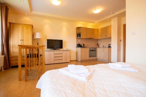 a bedroom with a large white bed and a kitchen at Parklands Hotel & Pool in Bansko