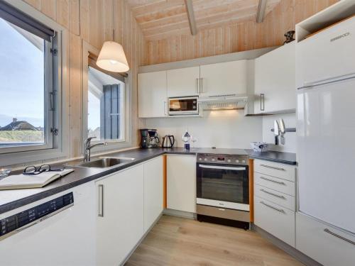 a kitchen with white cabinets and a large window at Holiday Home Durita - 600m to the inlet by Interhome in Havrvig