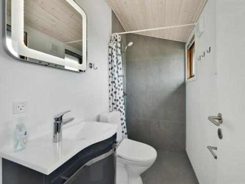 a bathroom with a sink and a toilet and a mirror at Holiday Home Leleks - 200m from the sea by Interhome in Hvide Sande
