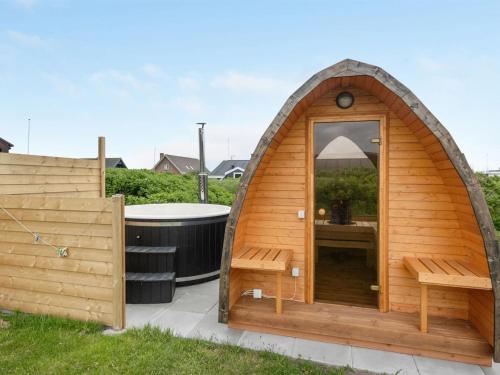a wooden iguana house with a tub in a yard at Holiday Home Leleks - 200m from the sea by Interhome in Hvide Sande