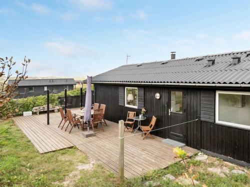 a wooden deck with a table and chairs on a house at Holiday Home Hélène - 400m from the sea by Interhome in Havrvig