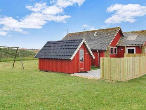 a red barn with a fence in a field at Holiday Home Beatrice - 150m from the sea by Interhome in Lemvig