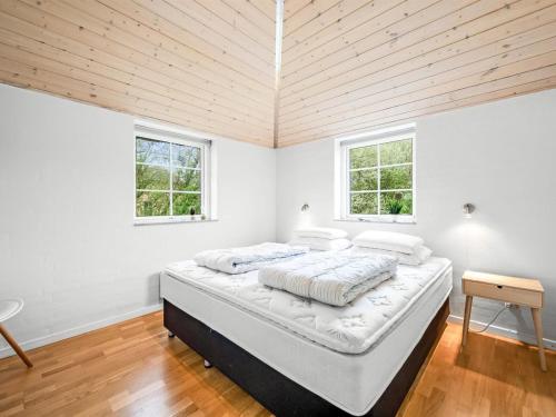 a bedroom with a bed with white walls and wooden ceilings at Holiday Home Benthe - from the sea by Interhome in Ulfborg