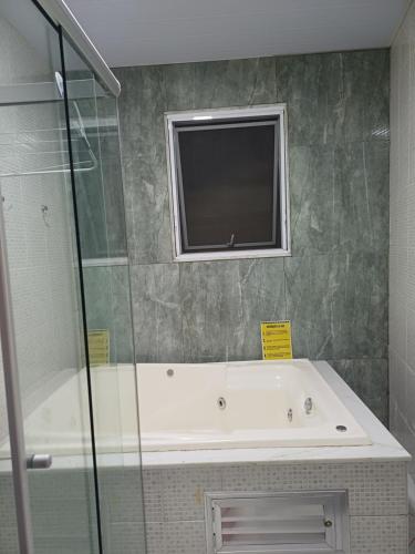 a bathroom with a bath tub and a window at Flat Cafofinho em MIGUEL PEREIRA in Miguel Pereira