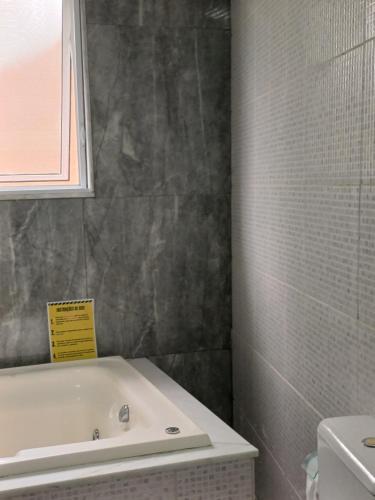 a bathroom with a bath tub and a sink at Flat Cafofinho em MIGUEL PEREIRA in Miguel Pereira