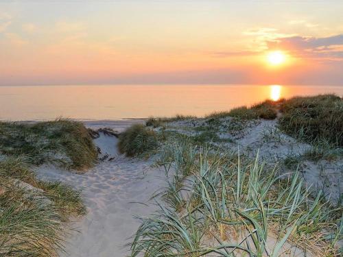 a sunset on a beach with footprints in the sand at Holiday Home Martinus - 5-5km from the sea by Interhome in Tim
