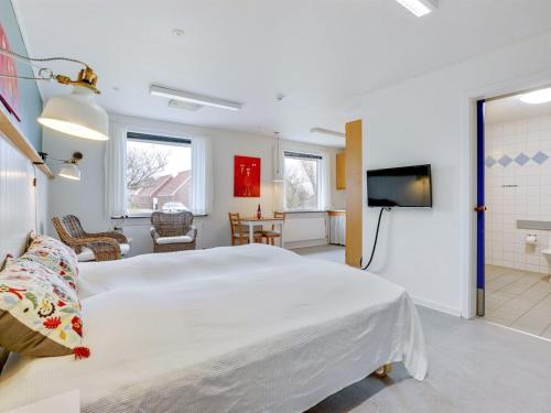a bedroom with a large white bed and a flat screen tv at Holiday Home Martinus - 5-5km from the sea by Interhome in Tim
