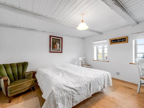 a white bedroom with a bed and a chair at Holiday Home Orvo - 150m from the sea by Interhome in Harboør