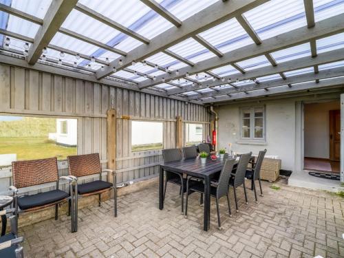 a patio with a table and chairs and a glass ceiling at Holiday Home Orvo - 150m from the sea by Interhome in Harboør