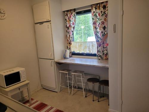 a kitchen with a counter and a refrigerator and stools at Hossanraitti in Kuusamo