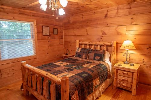 una camera con un letto in una baita di tronchi di Updated Cabin with 2 primary suites, hot tub, spacious covered porch a Fleetwood