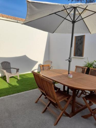 une table en bois avec un parasol sur une terrasse dans l'établissement Le rocher, à Longeville-sur-Mer