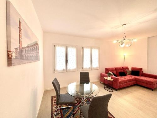 a living room with a red couch and a glass table at Casa fiorita in Camisano Vicentino