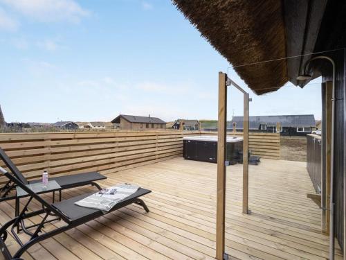 a deck with a chair and a table on it at Holiday Home Kristanna - 150m from the sea by Interhome in Harboør