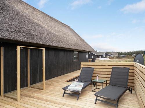 two chairs and a table on a wooden deck at Holiday Home Kristanna - 150m from the sea by Interhome in Harboør