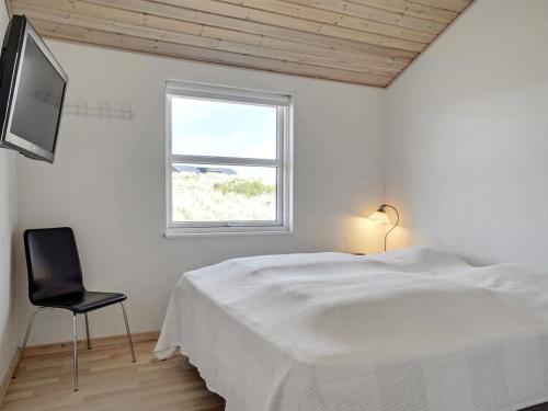 a white bedroom with a bed and a chair at Holiday Home Frido - 400m from the sea by Interhome in Torsted