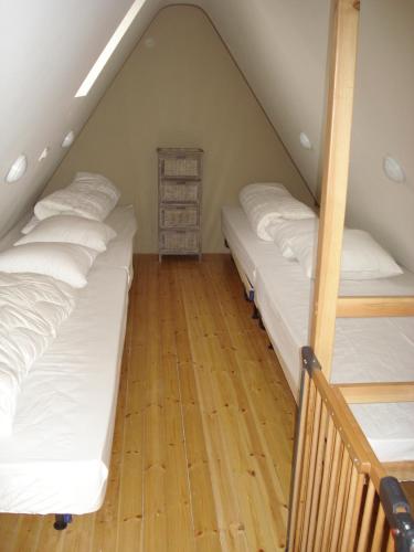 a attic room with three beds and a wooden floor at Holiday home Het Zeugekot in Beveren