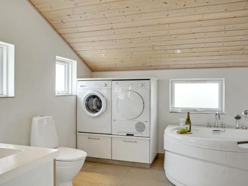 a white bathroom with a washing machine and a toilet at Holiday Home Frido - 400m from the sea by Interhome in Torsted