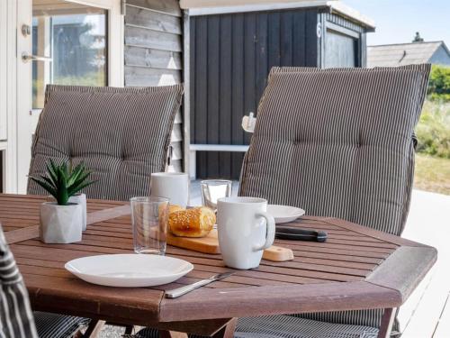 a wooden table with plates of food on a patio at Holiday Home Tameran - 700m from the sea by Interhome in Torsted