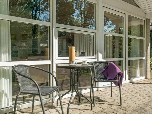 a porch with two chairs and a table with a candle at Holiday Home Aslak - 350m from the sea by Interhome in Torsted