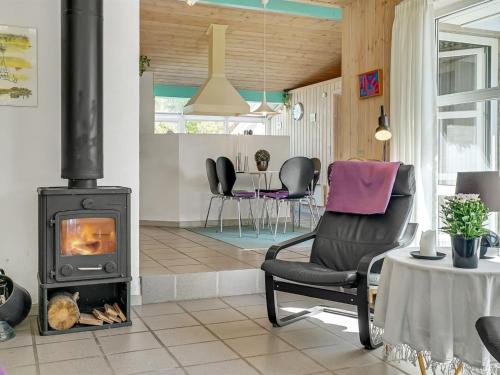 a living room with a fireplace and a chair at Holiday Home Aslak - 350m from the sea by Interhome in Torsted