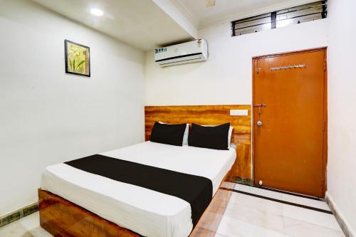 1 dormitorio con cama y puerta marrón en Hotel O Hotel New Hitech Inn, en Hyderabad