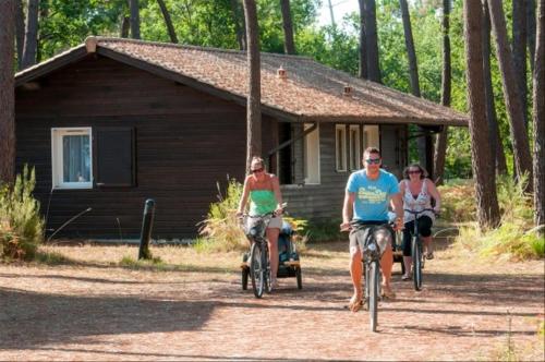 three people riding bikes in front of a cabin at Lacanau, 6 personnes, à côté du lac, sous les pins au calme in Lacanau