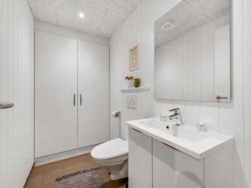 une salle de bains blanche avec toilettes et lavabo dans l'établissement Holiday Home Markku - 400m from the sea by Interhome, à Harboør