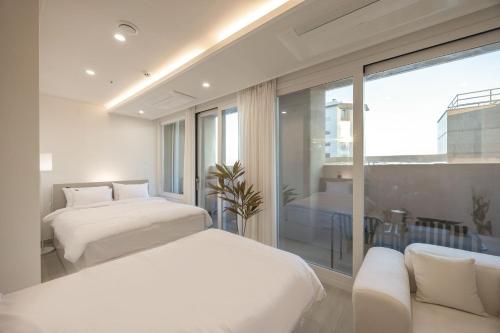 a bedroom with two beds and a couch and a window at 해운대 웨이브 Haeundae wave in Busan