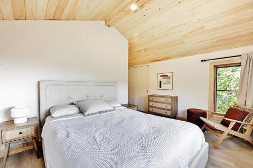 ストーンハムにあるChalets Alpins- 19 Chemin Alpinの白いベッドと木製の天井が備わるベッドルーム1室が備わります。