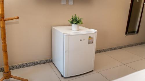 a white refrigerator with a plant on top of it at Pousada Itajuípe- Unidade Itabuna-Ba in Itabuna